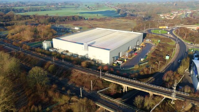 Sweeping aerial view of a massive distribution center and adjacent railway tracks in the Rugby industrial district.