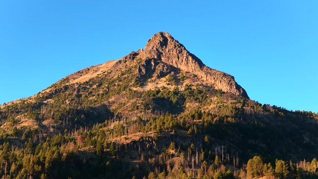 Nevado de Colima mountain peak reaching sky, forest ecosystem with rugged terrain