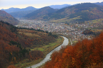 Fototapeta premium Scenic mountain valley town with a winding river and autumn foliage