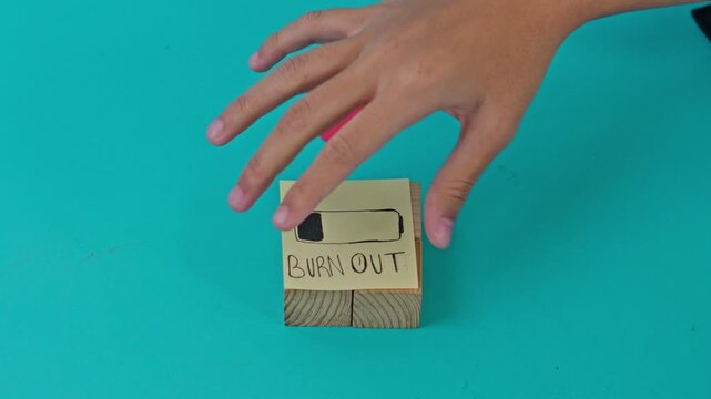 Hand placing "BURN OUT" note with low battery drawing onto wooden blocks