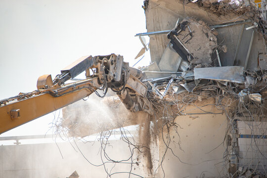 Construction site, demolition of reinforced concrete structure, gutting and renovation, hydraulic hammer dismantles building, caterpillar excavator machine