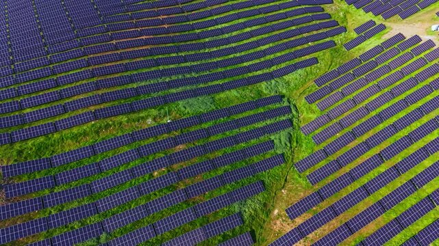 Rows of solar panels are set on a farm field under blue sky. The panels are positioned to maximize sunlight exposure for energy production.