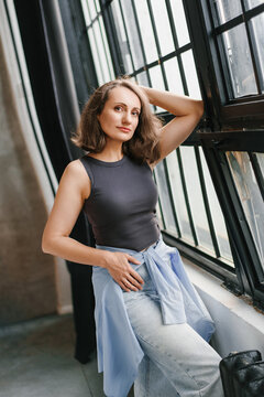 Confident Adult Woman Posing Near Large Loft Window