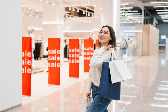 Happy Woman Carrying Shopping Bags Stands in Bright Mall Aisle