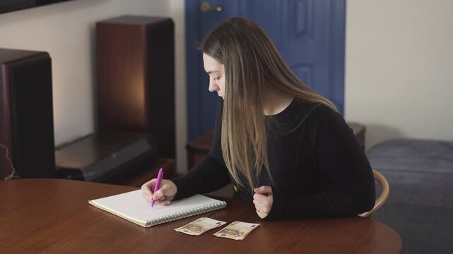 Young woman writes in a notebook at home beside tarot cards, creating a calm lifestyle, self-reflection, or planning concept.