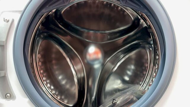 Close-up steel drum interior rubber seal visible, showroom display of new dryer drum with perforated stainless surface and circular