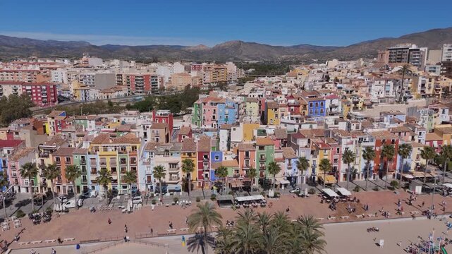 Ascending lateral drone shot of Villajoyosa colorful houses on Mediterranean coast