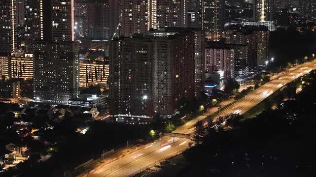 Nighttime long exposure of highway light trails beside highrise residential buildings.