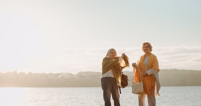 Senior friends enjoying peaceful sunset by water