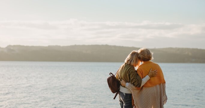Senior women friends embracing by the water