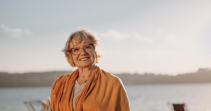 Senior woman smiling enjoying sunset by water