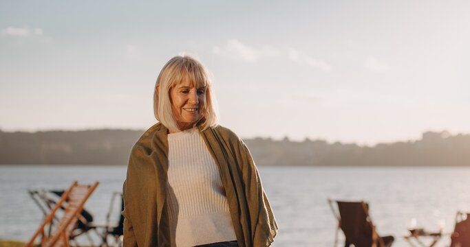 Senior woman relaxing by lake during sunset