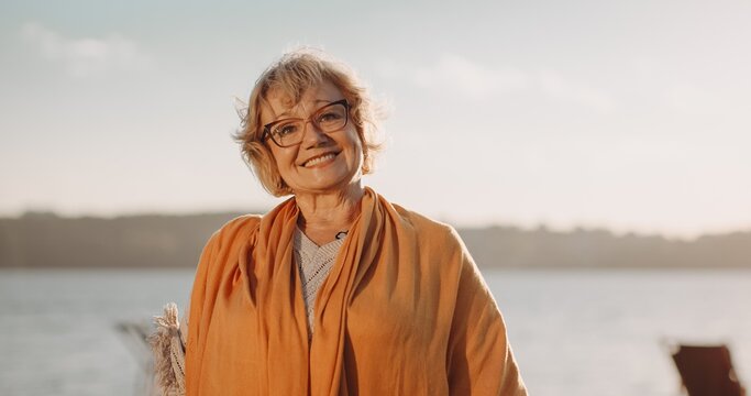 Senior woman smiling enjoying sunset by water