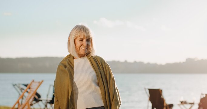 Senior woman smiling by lake enjoying leisure time