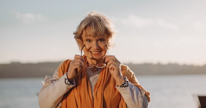 Senior woman smiling holding glasses outdoors