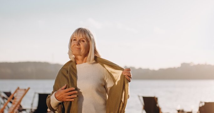 Senior woman relaxing by lake at sunset