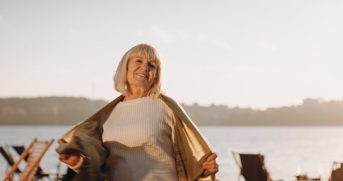 Senior woman smiling embracing outdoors during sunset