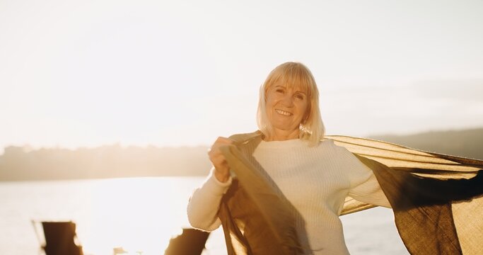Senior woman smiling with scarf at sunset