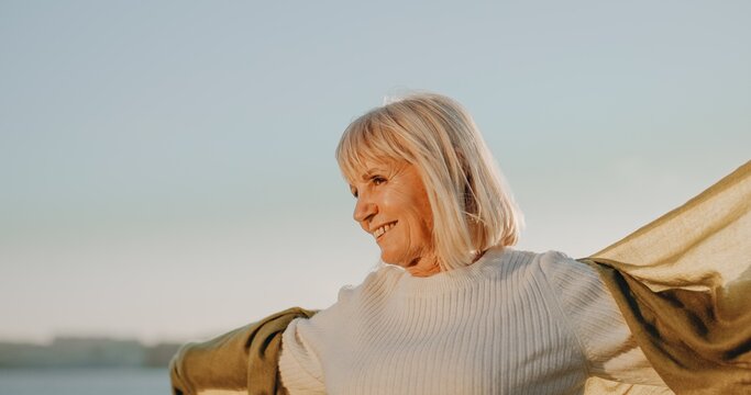 Senior woman smiling embracing freedom outdoors at sunset