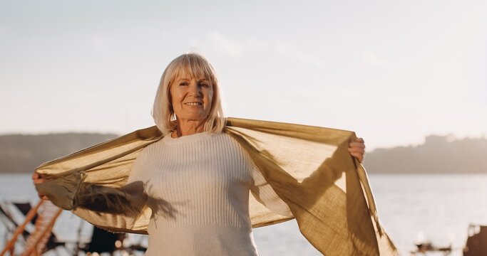 Senior woman smiling with scarf outdoors enjoying nature