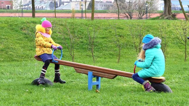 Two girls swinging on a swing in the park in autumn near the old town of Zamosc, Poland.