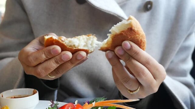 Hands hold bread bun at local cafe in morning
