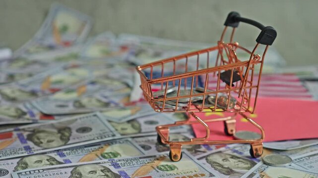 Coins falling onto trolley with background of one hundred dollar bills
