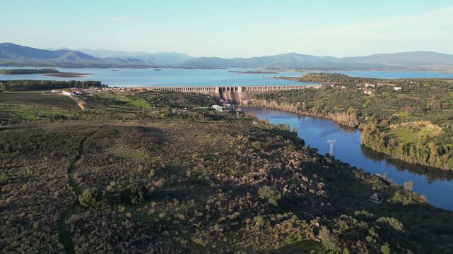 Aerial drone view of Gabriel y Gal&aacute;n dam and reservoir at sunset, with river, mountains and rural landscape in Extremadura, Spain.