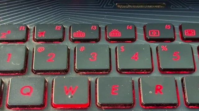 Finger typing on laptop keyboard in "3" button, glowing red keys highlighting technology theme.