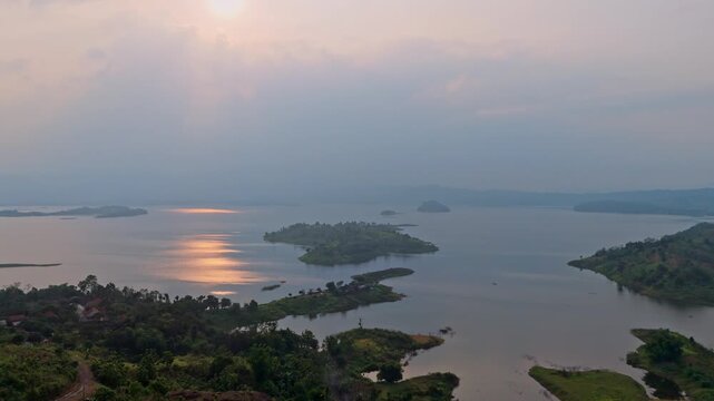 Serene tropical lake scenery with small islands and lush hills under hazy twilight sky