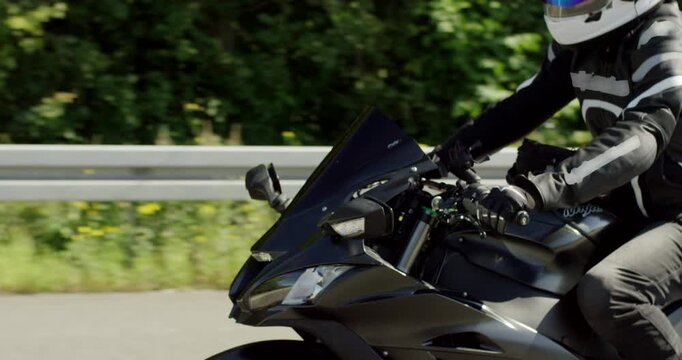 Close-up profile of a motorcyclist in a white helmet riding a sport bike along a sunny highway