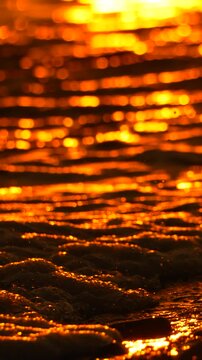 Sunset water bokeh, shimmering golden orange texture reflects the abstract light on the ocean surface. Vertical video