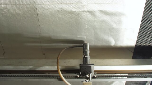 Laser device perforates fabric creating sewing markers. Highlighting advanced technology employed in today garment assembly at factory