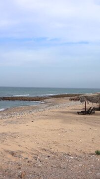Beach Solitude Scene. Quiet Sandy Cove With Umbrellas. Arabian Gulf Calm Beach With Shallow Surf And Open Chairs. Serene Coastal Area Featuring Straw Umbrellas And Vacant Seating Spots