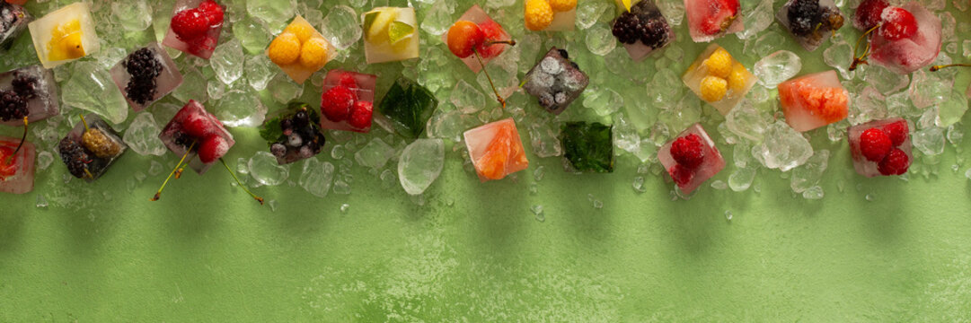 Green background with ice cubes with frozen berries and fruits and mint, banner