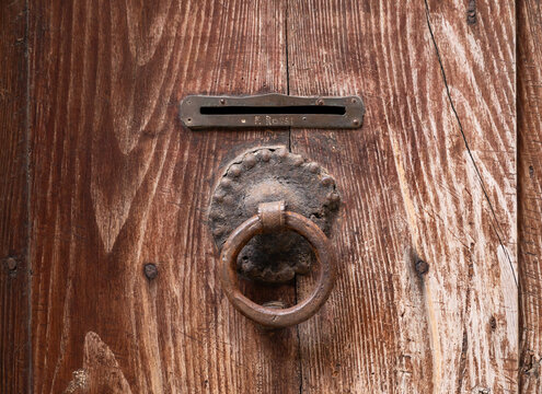 Old wooden door featuring rustic knocker and mail slot