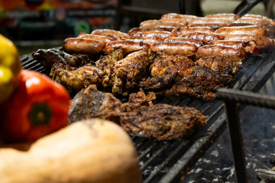 Grilled Meats and Sausages with Blurred Vegetables in Foreground