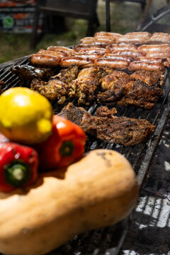 Grilled Meat and Sausages on a Barbecue with Blurred Peppers and Lemons