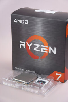 A close-up of an AMD Ryzen 7 5800X processor in a packaging box with backlit keyboards in the background.