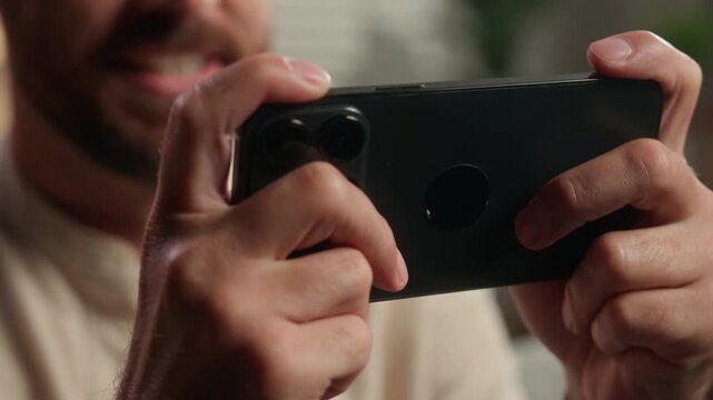 Close up unrecognizable Caucasian man playing mobile phone game unknown male gamer user play virtual gaming with smartphone app at home guy holding cellphone having fun entertainment gadget addict
