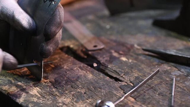 A worker uses a file to remove metal shavings from the edge of a hole in a product. Handmade.