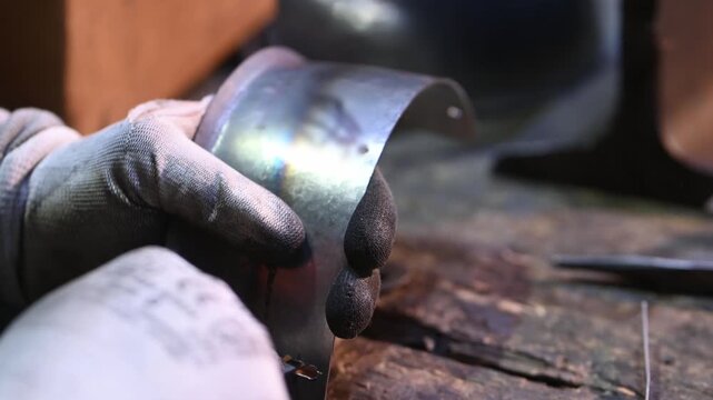 A worker uses a file to remove metal shavings from the edge of a hole in a product. Handmade.