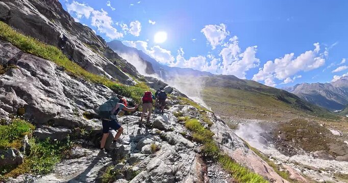 Hiking group ascending beside Pitztal waterfall in Alps Austria