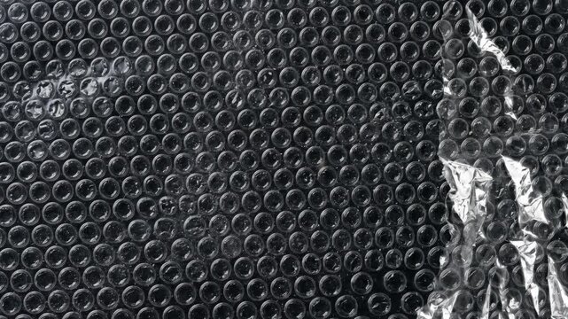 Abstract View of Torn Bubble Wrap Moving on Black Background
