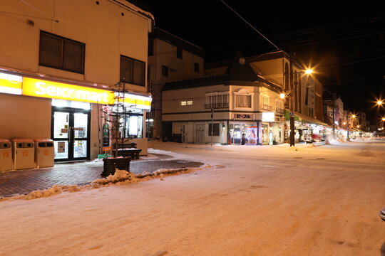 Snowy street corner with Seicomart convenience store at night.