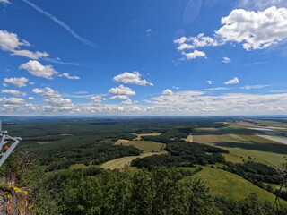 Fototapeta premium Aerial panoramic view of vast agricultural fields and lush green forests with cloud shadows under a beautiful summer sky, rural landscape.