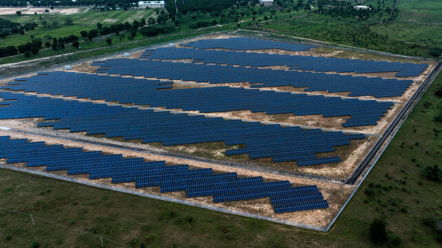 Aerial view of a vast solar farm, dark panels creating geometric patterns against the earthy ground and green foliage, Maiduguri, Borno, Nigeria.