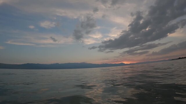 Peaceful sunset over Lake Shkoder in Albania with calm water surface and mountains in background. Beautiful evening landscape.