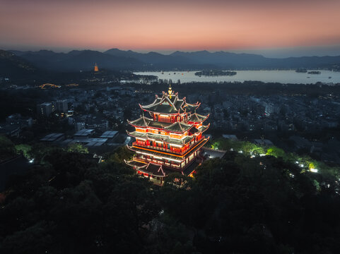 Aerial view of the illuminated Leifeng Pagoda rises majestically against the dusk sky, a beacon of ancient splendor, Hangzhou, Zhejiang, China.