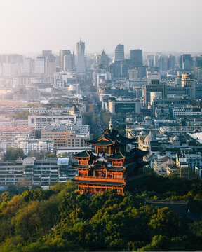 Aerial view of a traditional pagoda on a green hill, contrasting with a sprawling modern city, Hang Zhou Shi, Zhe Jiang Sheng, China.
